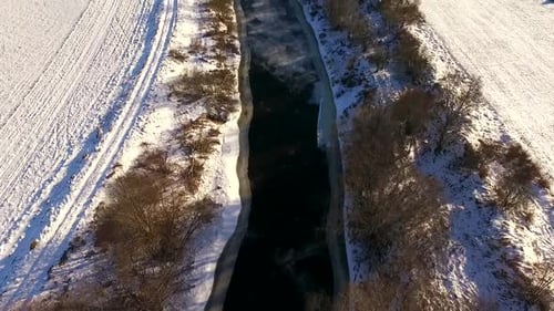 Aerial view of Vaana Jogi river surrounded by snow in winter in Estonia.
