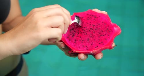 Woman Eats Vibrant Dragon Fruit by Turquoise Pool