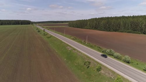 Luftaufnahme eines schwarzen Personenkraftwagens, der auf einer geraden Asphaltstraße fährt 03