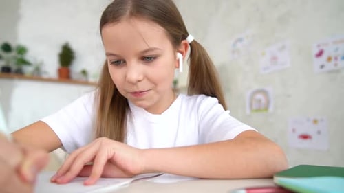 Smiling Girl Writes at Desk in Bright Home