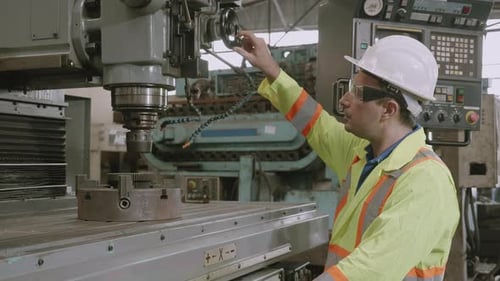 Young asian engineer man working and control machine with system at industrial factory.