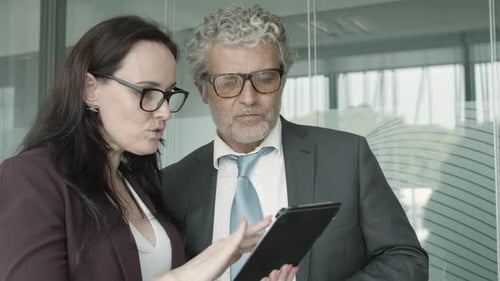 Professionals Discussing Business on Tablet in Office