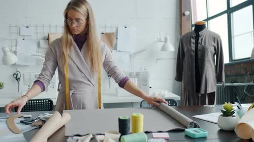 Fashion Designer Unrolling Fabric in Bright Studio