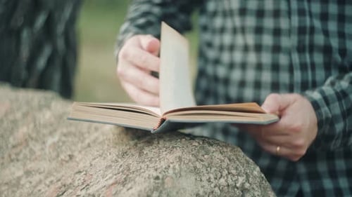 Homme lisant et tournant la page d'un livre de texte. - gros plan