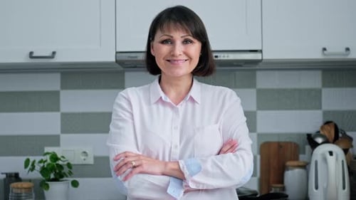 Woman Smiling in Kitchen with Arms Crossed