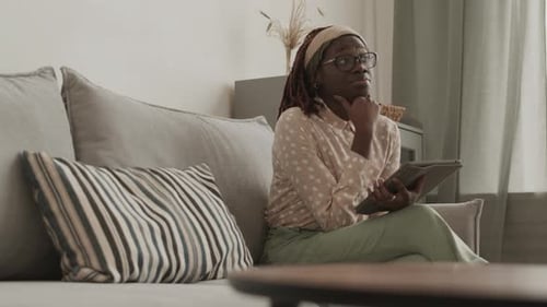 Woman Uses Tablet Device on Gray Sofa