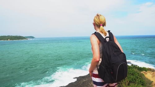 The Girl Stands on The Edge of The Rock and Looks at The Sea Waves. Tropical Island Trip