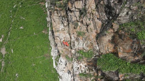 Woman Athlette Climbing on the High Rock in the Mountains