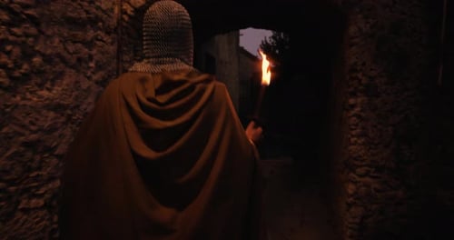 Knight Walks with Torch Through Stone Passageway