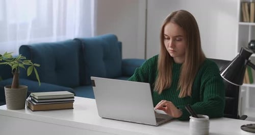 Woman Working on Laptop at Desk in Bright Room