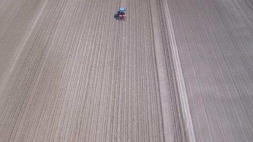 Tractor in a field ploughing, countryside aerial view