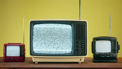 Three Vintage Televisions Showing Static on Screens