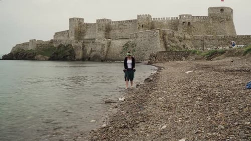 A woman hardly trying to walk on the pebbles on the rocky seaside
