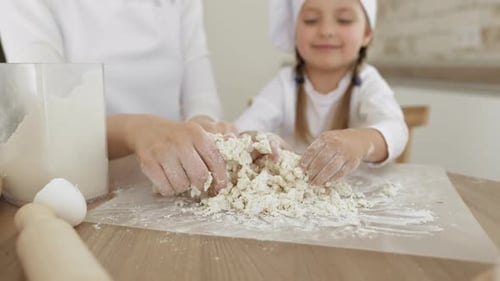 Imagem de perto Mulher e filha amassam massa com as mãos Mesa de madeira em pó com farinha