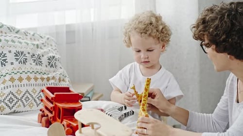 Mother and Child Playing with Toys on Bed
