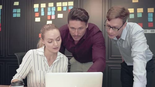 Three Young Adults Collaborating on a Laptop in Office