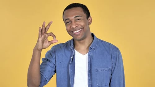 Young Adult Makes OK Hand Gesture on Yellow