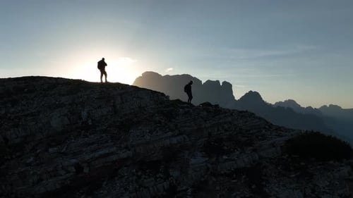 Female and male hikers at the top of the mountain at sunrise.