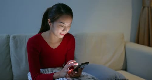 Woman using Smartphone Indoors on Couch at Night