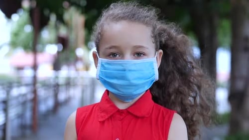 Cute Little Girl Standing on a Street in Protective Masks From the Covid-N1H1 Epidemic. Concept of