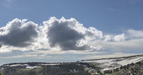 Time Lapse of Cloudscape Behind of the Mountains Top. Snow, Rocks, Cliffs and Deep Blue Sky. High