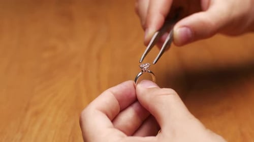Nahaufnahme eines Juweliers fügt einen Diamanten in den Ring ein