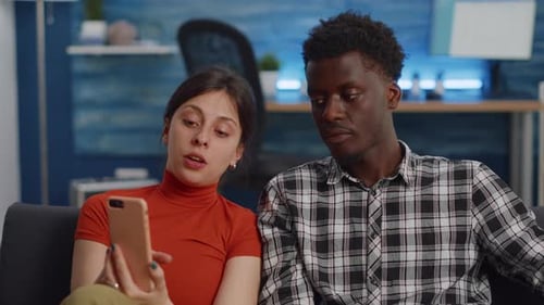 Couple Using Mobile Phone Together on Sofa