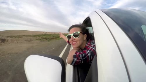 Happy Woman Leaning Out Car Window on Road Trip