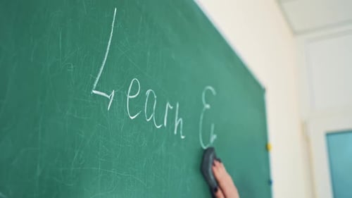 Hand Erases Chalkboard in Classroom Setting