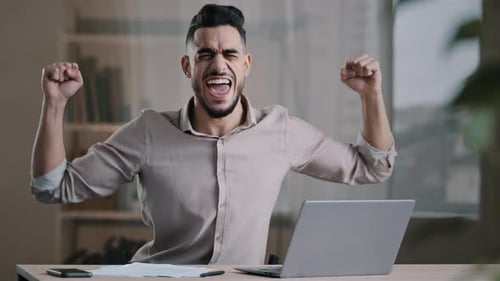 Excited Young Adult Man Celebrating Success at Computer