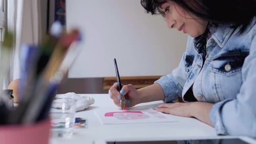 Young female artist painting on canvas inside art home studio