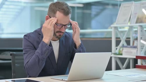 Man Experiencing Headache While Working on Laptop