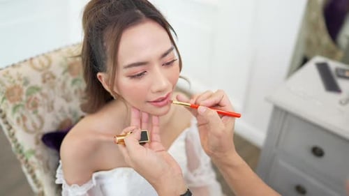 4K Asian guy make-up artist applying makeup to female bride in white wedding dress.