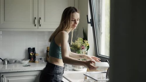 Woman Doing Dishes in Bright Kitchen