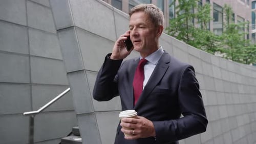 Businessman Talking on Cellphone While Walking on City Street