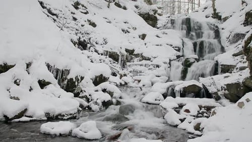 Wonderful frozen foot of a waterfall with a powerful stream of water at winter carpathian mountains