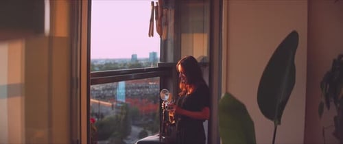 Woman Taking Pictures on Apartment Balcony at Sunset