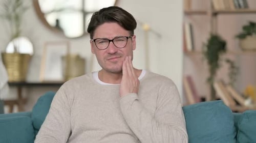 Man Experiences Toothache on Couch at Home