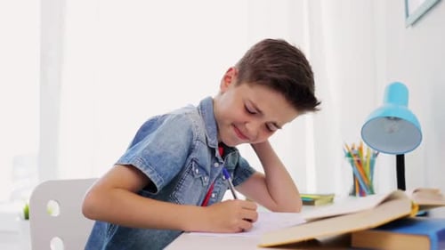 Boy Writes in Notebook at Desk