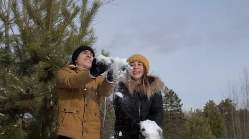 Couple fille et gars se jettent de la neige dans la forêt d'hiver au ralenti