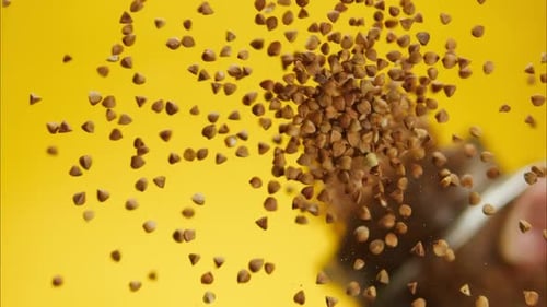 Buckwheat Groats Falling on Yellow Surface