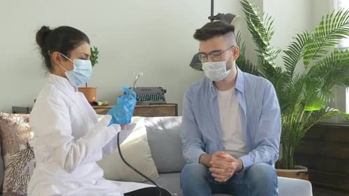 Doctor Checking Young Man's Pulse with Stethoscope