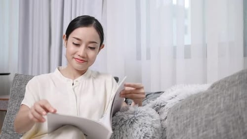 Woman Relaxing on Sofa Reading Magazine