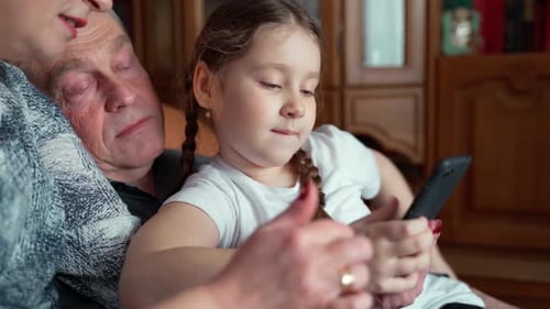 Little Girl Using Phone with Family Indoors