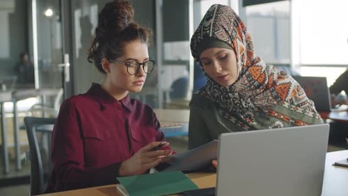 Two Young Women Collaborating in Modern Office