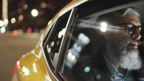 Hombre de mediana edad hablando por teléfono mientras viaja en taxi