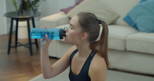 Woman Drinking Water after Exercise at Home