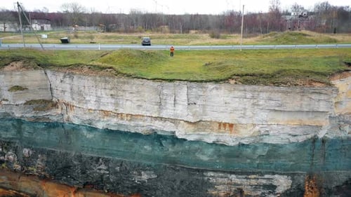 Drone Is Flying Away From Young Man with Remote Control To Reveal Amazing Eroded Rocky Sea Shore