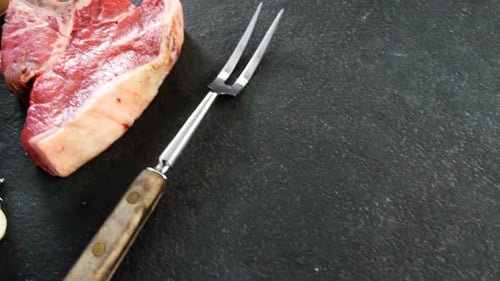 Raw T-Bone Steak with Seasonings and Meat Fork