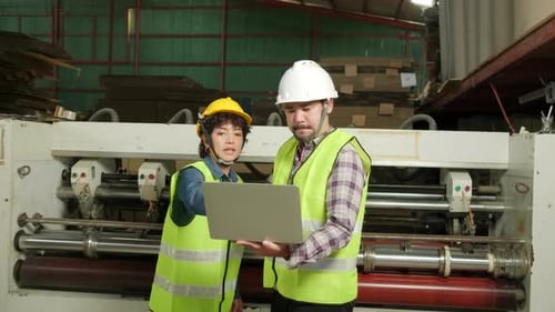 Factory Workers Inspecting Machinery with Laptop